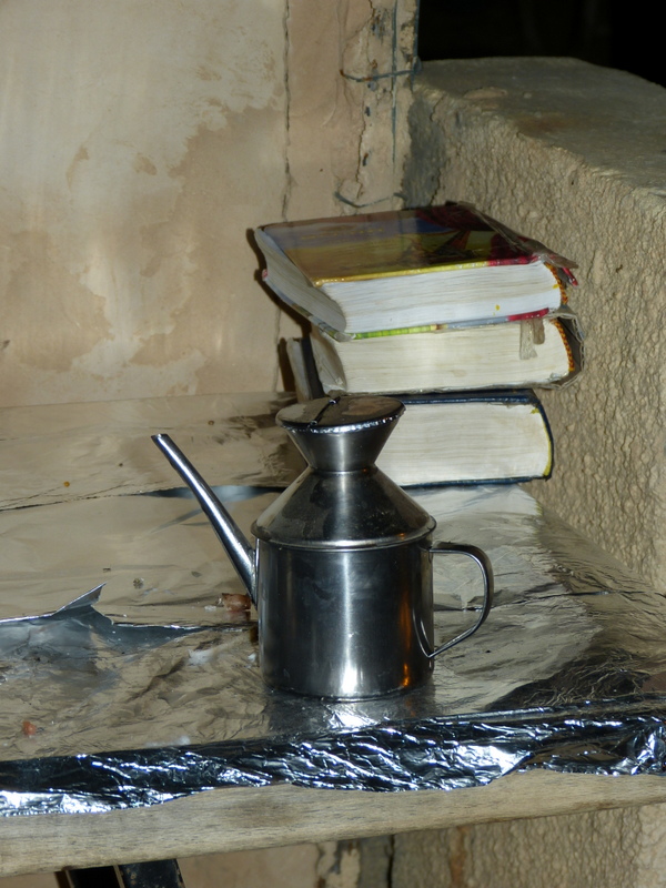 Olajtartó kanna és imakönyvek várják egy ház elé kitett asztalon a gyertyagyújtást.
