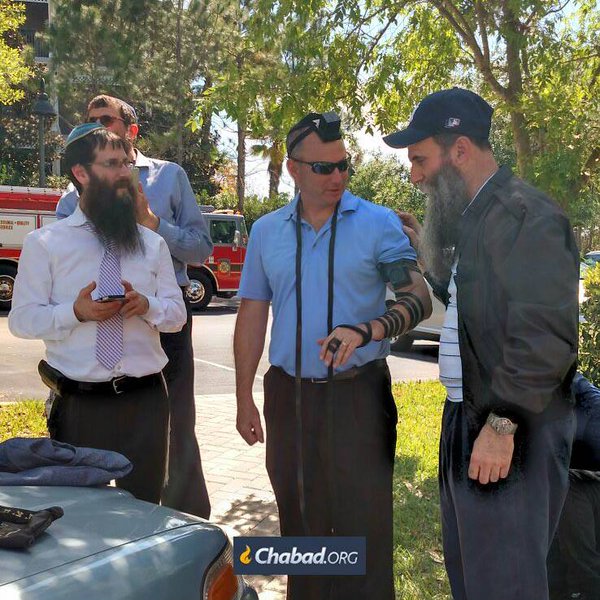 A szállodaigazgató tfilint rak két chábád rabbi segítségével