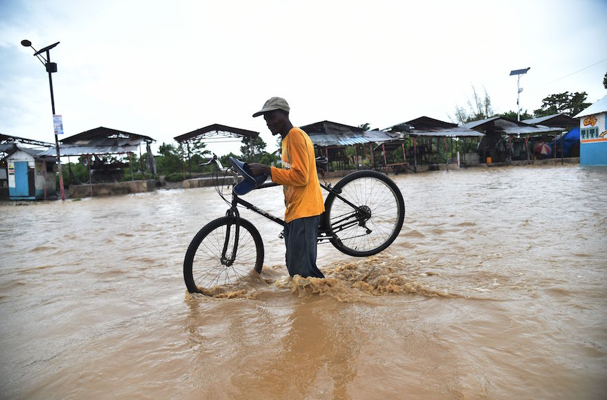 A man tries to cross the overflowing of the river Rouyonne, in the commune of Leogane Port-au-Prince, on October 5, 2016. Haiti and the eastern tip of Cuba -- blasted by Matthew on October 4, 2016 -- began the messy and probably grim task of assessing the storm's toll. Matthew hit them as a Category Four hurricane but has since been downgraded to three, on a scale of five, by the US National Hurricane Center.  / AFP / HECTOR RETAMAL        (Photo credit should read HECTOR RETAMAL/AFP/Getty Images)