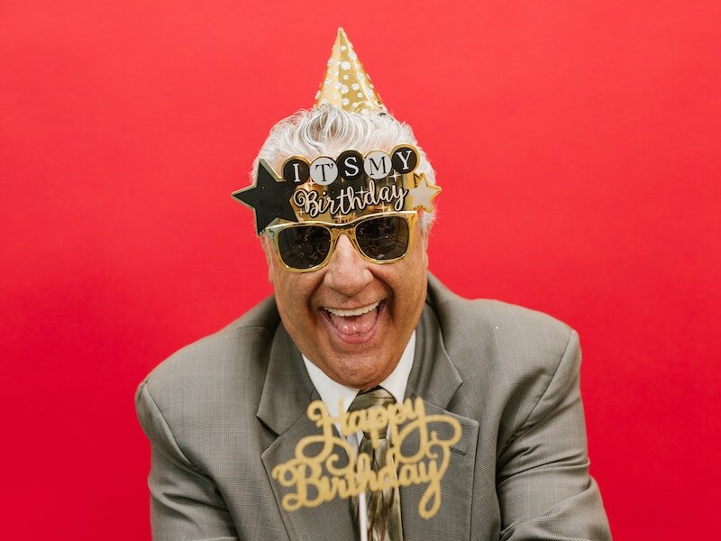 A Cheerful Elderly Man in Gray Suit Celebrating His Birthday