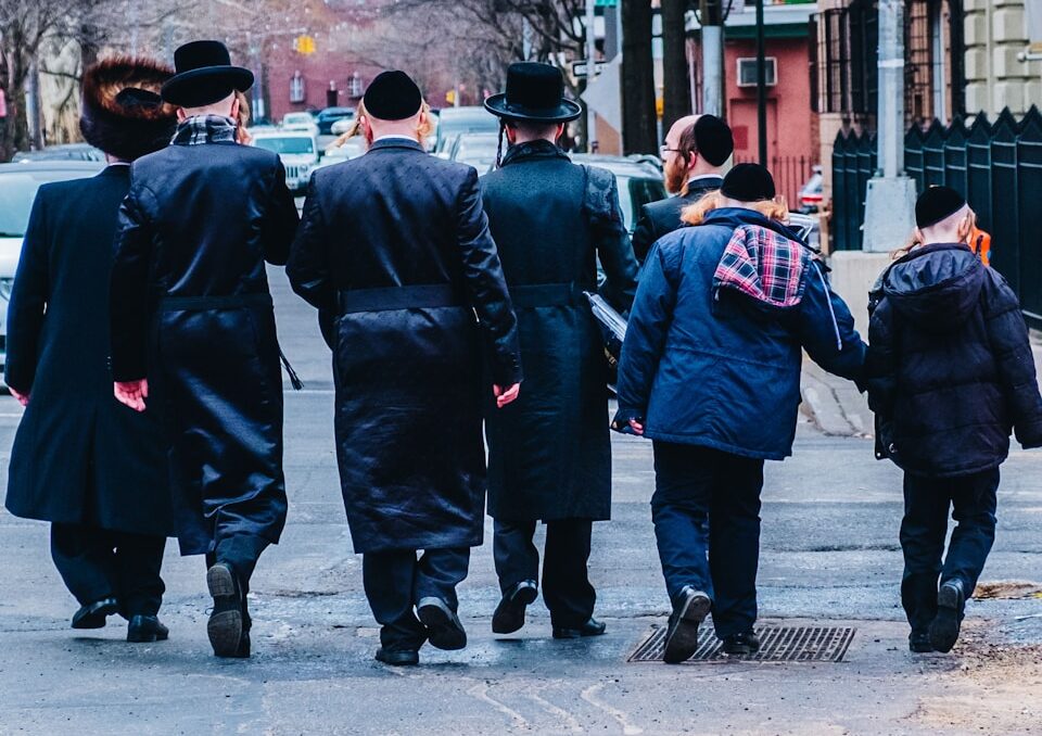 group of men in black coat walking on sidewalk during daytime